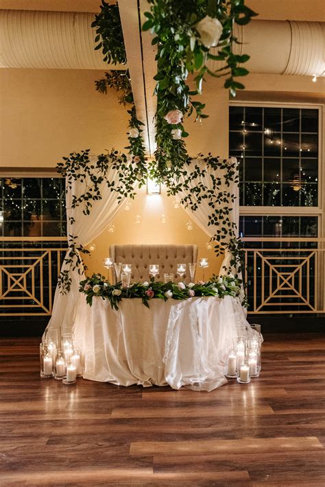 Sweetheart Table With Draped Arch Backdrop With Cascading Greenery And