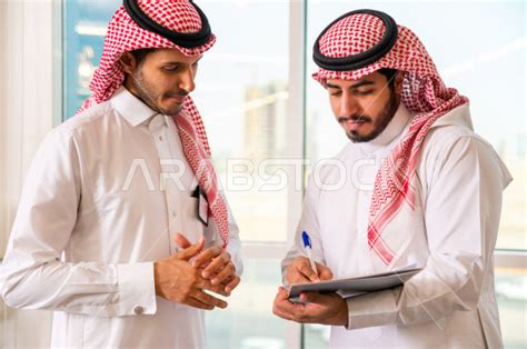 رجال اعمال سعوديين يتحدثون و يتناقشون في عقد العمل في مقر الشركة ، توقيع عقد عمل ،اتفاقية و صفقة