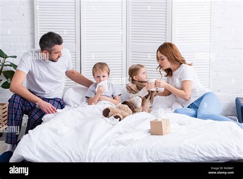 Parents Taking Care Of Sick Daughter And Son In Bedroom Stock Photo Alamy