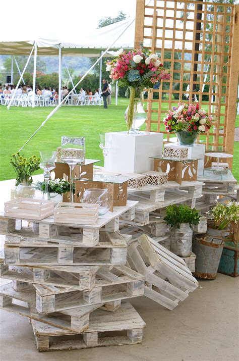 The Table Is Made Out Of Pallets And Has Flowers In Vases On It