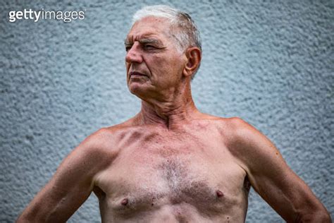 Shirtless Senior Man Standing In Front Of A Wall
