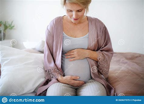 Happy Pregnant Woman Stroking Her Belly Sitting On Bed Stock Image
