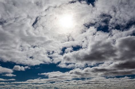 White Fluffy Clouds Covering Bright Sun In Skies Background Pattern