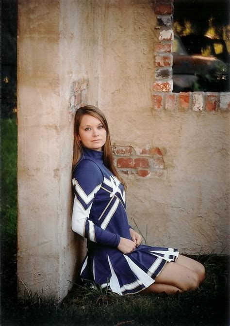 A Woman In A Blue And White Dress Sitting On The Ground Next To A Brick