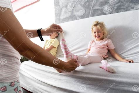 Mom Takes Off Her Little Daughter`s Socks And Tickles Her Feet A Little The Girl Laughs Stock