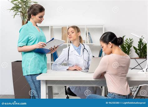 Patient Sitting In Chair And Talking With Doctor And Nurse In Medical