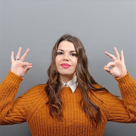 Portrait Of Happy Woman Showing Ok Sign Against Gray Background Stock