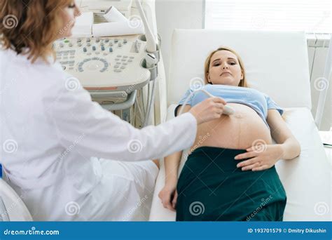 Female Doctor Examines Abdominal Of Belly Of Lying Pregnant Young Woman