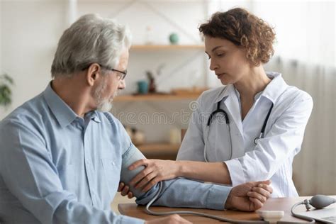 Female Doctor Measuring Senior Patient Blood Pressure At Hospital Stock