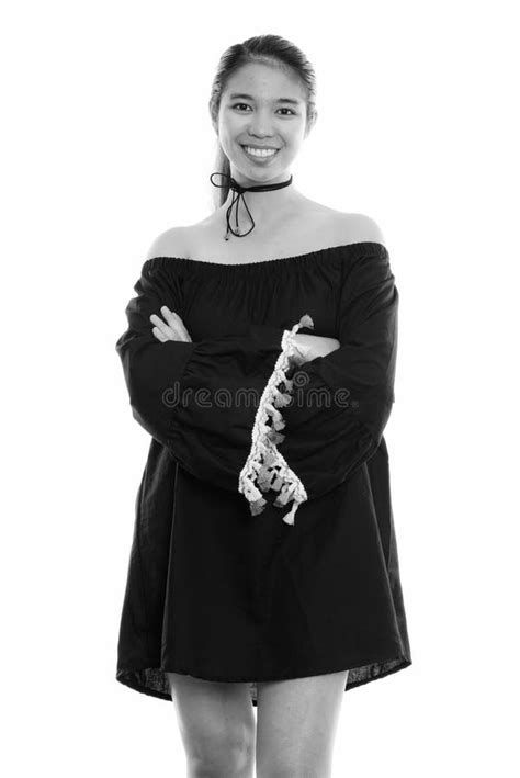 Studio Shot Of Young Happy Asian Woman Smiling And Standing With Arms
