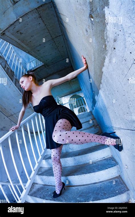 spreading arms and legs standing on steep staircase steps serious looking away aside leg raised