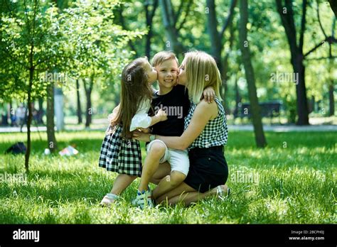 feliz madre hija e hijo se enhudándose unos a otros en un parque la madre y su hija besan a un