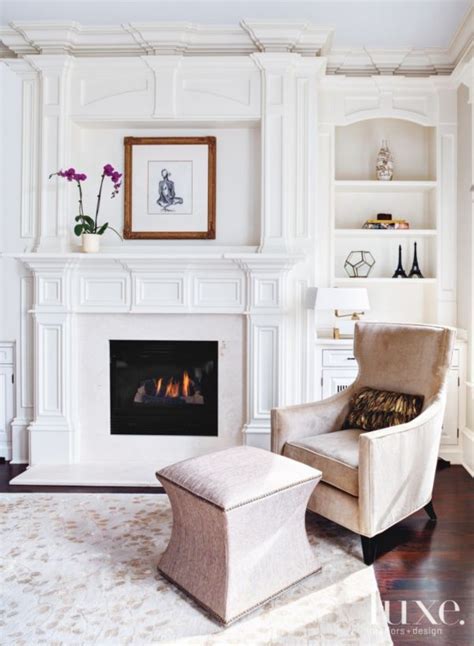 In This Neutral Living Room A Cozy Chair Sits By A Fireplace With A