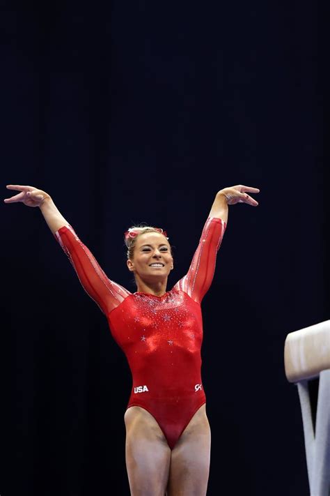 A Woman In A Red Leotard Is Standing On The Balance Beam With Her Arms Outstretched