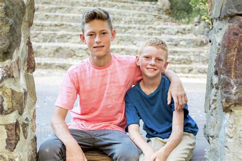 Older brother with arm around younger brother sit for portrait - Stock ...
