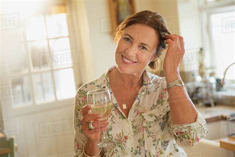 Portrait Smiling Mature Woman Drinking White Wine In Kitchen Stock