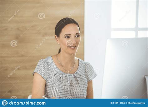 cheerful smiling businesswoman working with computer while sitting at the desk in modern office