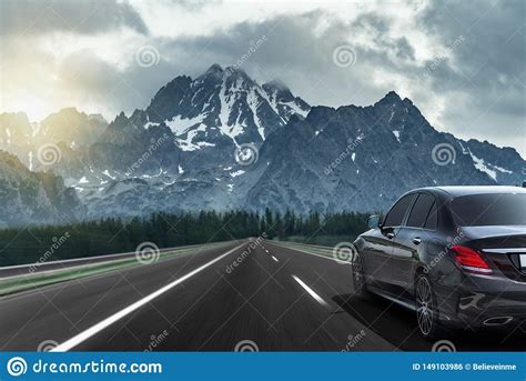 The Car Drives Fast On The Highway Against The Backdrop Of A Mountain