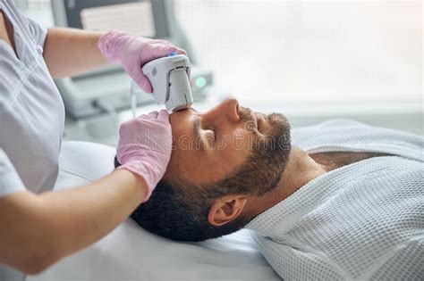 Doctor Cosmetologist Treating Male Skin With Laser Device Stock Image