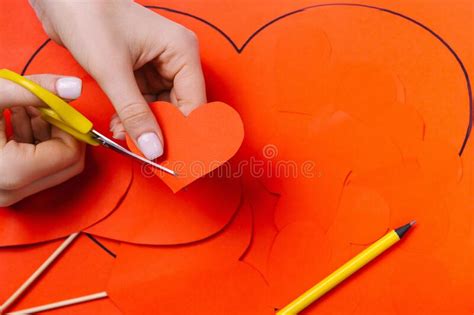 Womenand X27s Hands Cut Out A Red Heart On The Background Of A Pencil