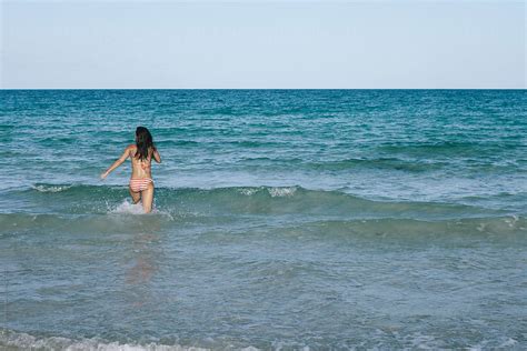 Babe Woman In Bikini Wading In Water At The Beach In Summer By Stocksy Contributor Joselito