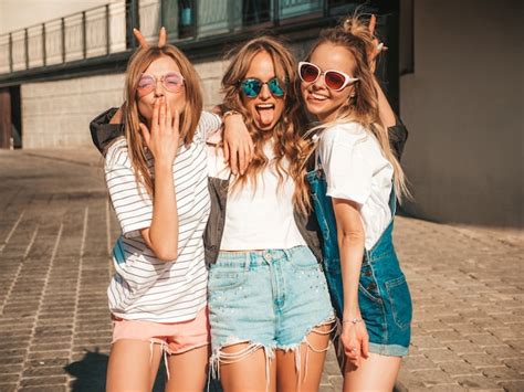 トレンディな夏服の3人の若い美しい笑顔流行に敏感な女の子の肖像画。セクシーな屈託のない女性が通りをポーズします。サングラスで楽しんでいる肯定的