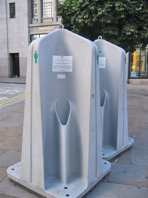 Two White Urinals Sitting On The Side Of A Street Next To A Tree