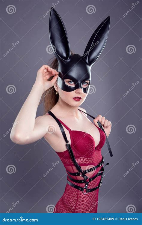 Woman Posing In A Black Bdsm Mask Bodysuit And Leather Holster Stock