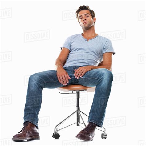 Portrait Of Smart Young Man Sitting Comfortably On Chair Against White