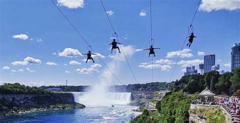 Some People Are Hanging From Wires Above The Water And Waterfall While Others Watch In The Distance