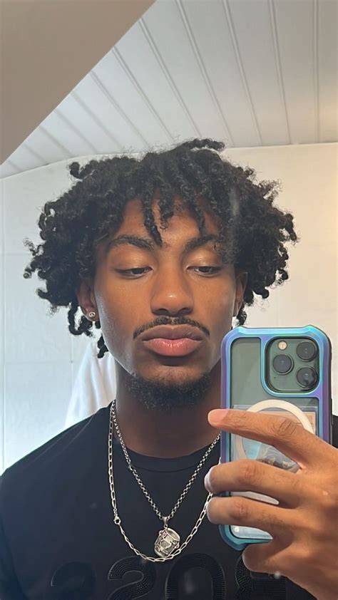 a man with curly hair is holding up his cell phone to take a selfie