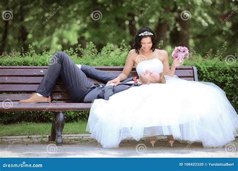 Жених и невеста на скамейке в парке Стоковое Фото изображение насчитывающей стенд платье