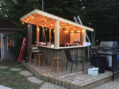 An Outdoor Bar Is Lit Up With String Lights And Some Stools On The Deck