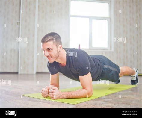 Portrait Of Sporty Smile Man Doing Planking Exercise On Mat In Room