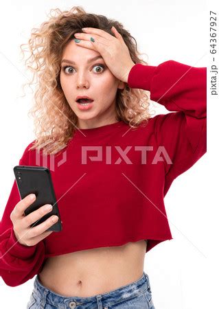 surprised curly blonde girl with a phone in his の写真素材 PIXTA