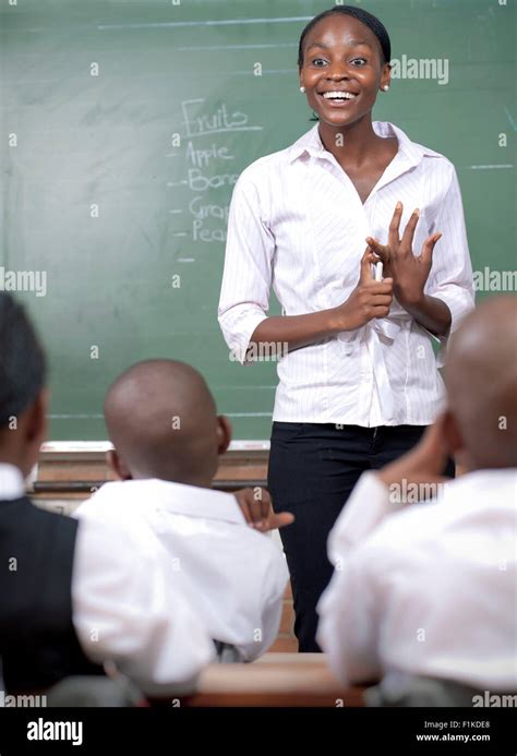 African Teacher Writing On A Chalkboard Teaching Her Class Stock Photo
