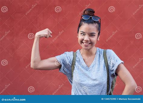 Young Asian Woman Smiling While Humorously Flexing Her Bicep Outside