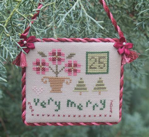 a cross stitch ornament hanging from a tree
