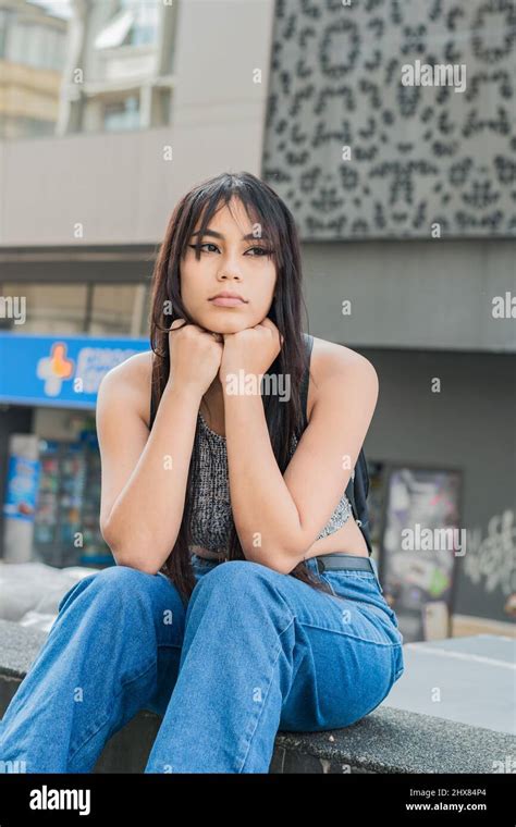 Beautiful Latin Woman With Brown Skin Sitting On The Sidewalk In The
