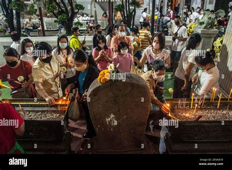 Buddhist Devotees Light Candles While Holding The Lotus To Be Placed At