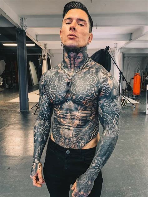 a man with tattoos on his chest standing in a garage
