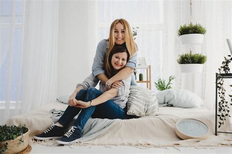 Free Photo Two Adult Sisters Hug Each Other Tender Sitting On The White Bed