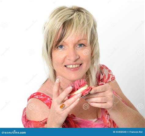 Beautiful Senior Woman In Pink Dress Eating Yellow And Pink Macaroon