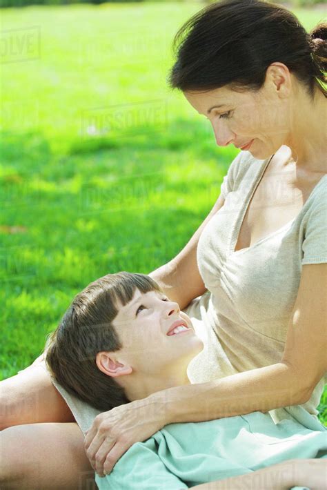 Boy Resting Head On Mothers Lap Smiling At Each Other Stock Photo