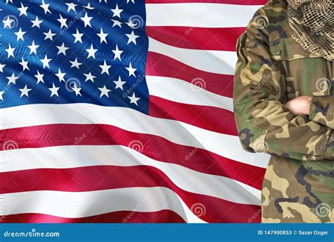 Crossed Arms American Soldier With National Waving Flag On Background