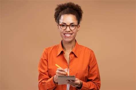 premium photo cheerful woman wearing eyeglasses smiles at camera posing with notepad isolated