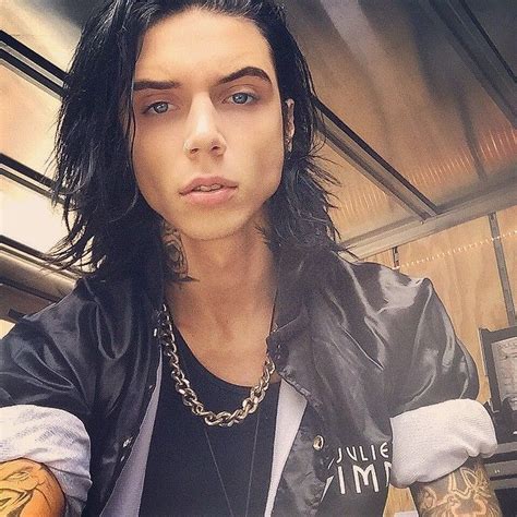 A Man With Long Hair And Piercings On His Arm Wearing A Leather Jacket
