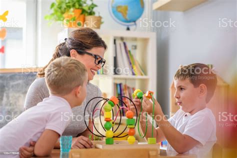 Preschool Teacher With Children Playing With Didactic Toys Stock Photo