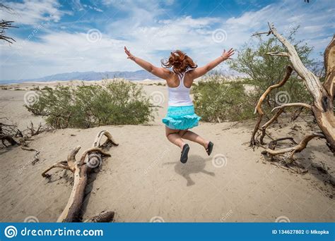 Young Adult Female Woman Jumps In The Mesquite Sand Dunes In Death