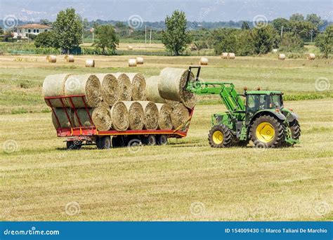 Tractor Loading Round Bales Of Hay On Trailer For Transport To